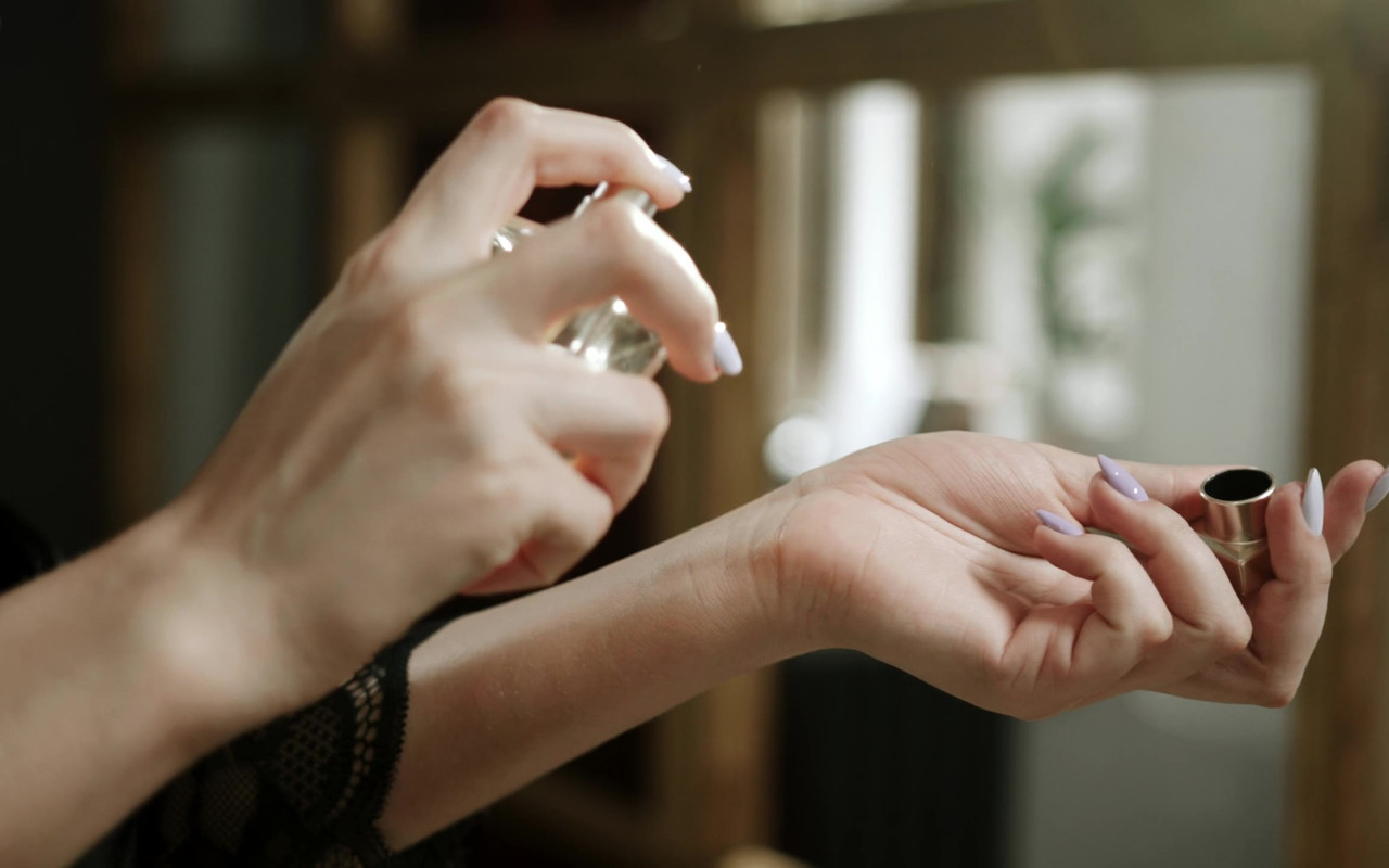 Mujer aplicándose perfume en la muñeca